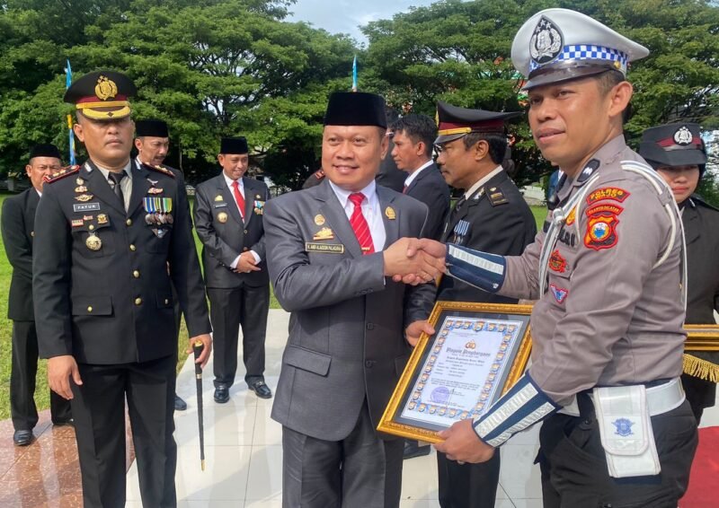 Ketua DPRD Wajo H. Andi Alauddin Palaguna menyerahkan penghargaan kepada salah-satu personil Polres Wajo yang berprestasi pada upacara hari Bahayangkara ke 77 di Lapangan Upacara Kantor Bupati Wajo, Sabtu 1 Juli 2023
