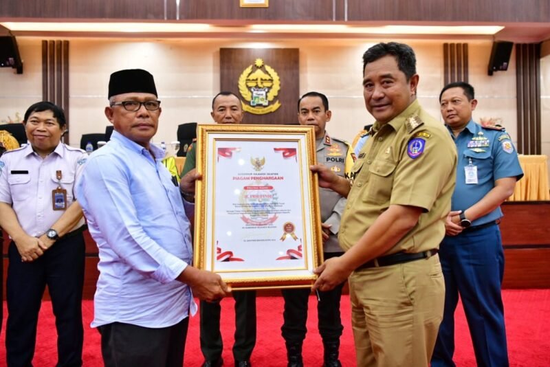 Penjabat Gubernur Sulsel, Bahtiar Baharuddin, memberikan penghargaan kepada Haji Amir Bandu, warga Kabupaten Bone yang mengibahkan tanah miliknya kepada Lantamal VI Makassar di Ruang Pola Kantor Gubernur Sulsel, Rabu, 27 Desember 2023
