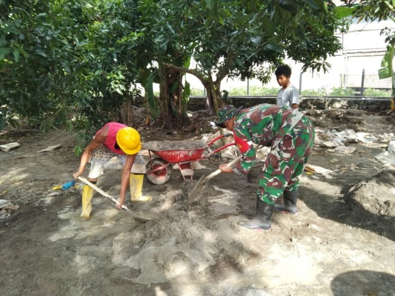 Personel Babinsa Koramil 1406-10/Pitumpanua, Serda Firman, turun langsung membaur bersama warga dalam aksi karya bakti pembersihan ruas jalan desa pada Minggu (8/2/2026)